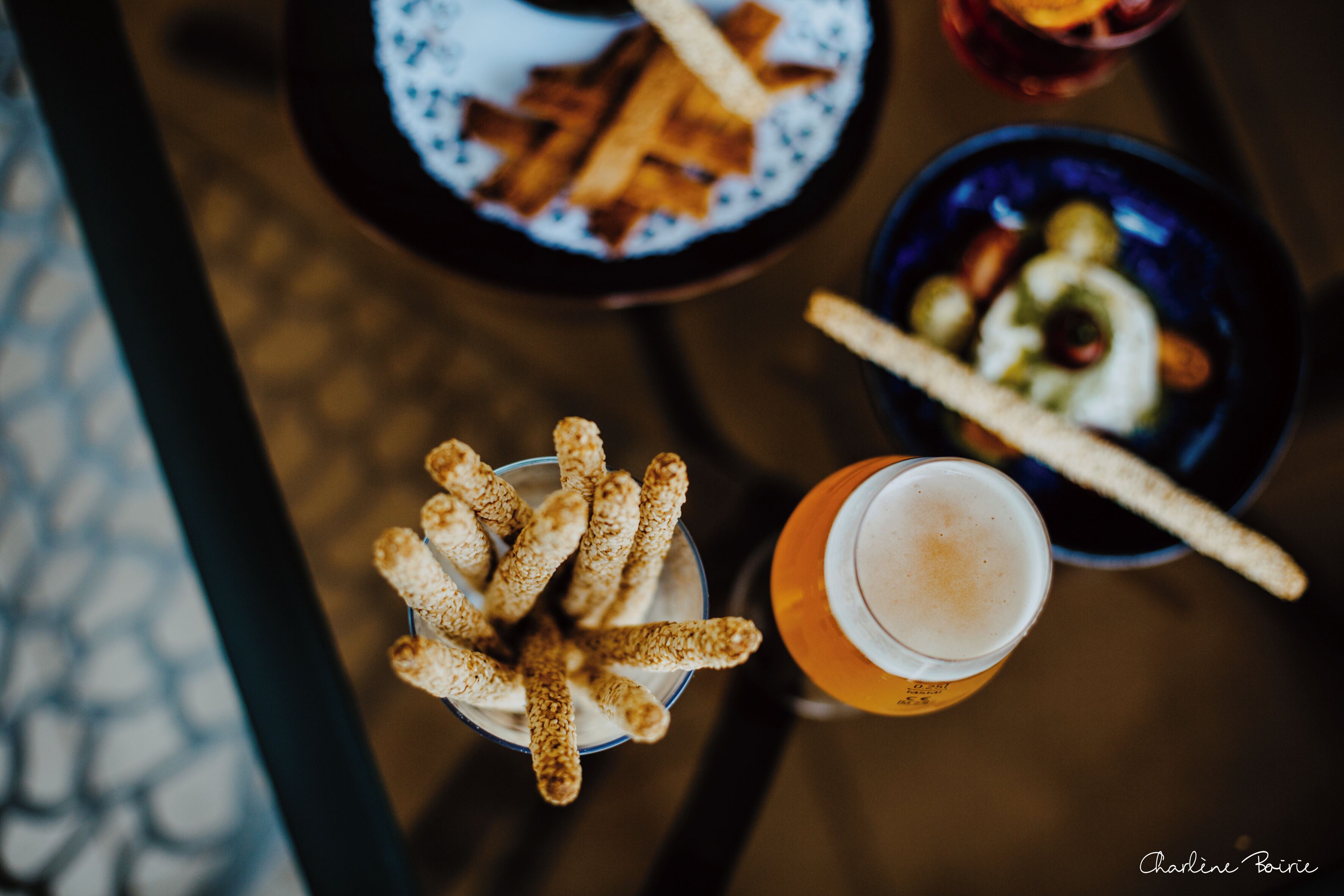 Une table avec un verre de bière, un bol de bretzels et une assiette de frites.