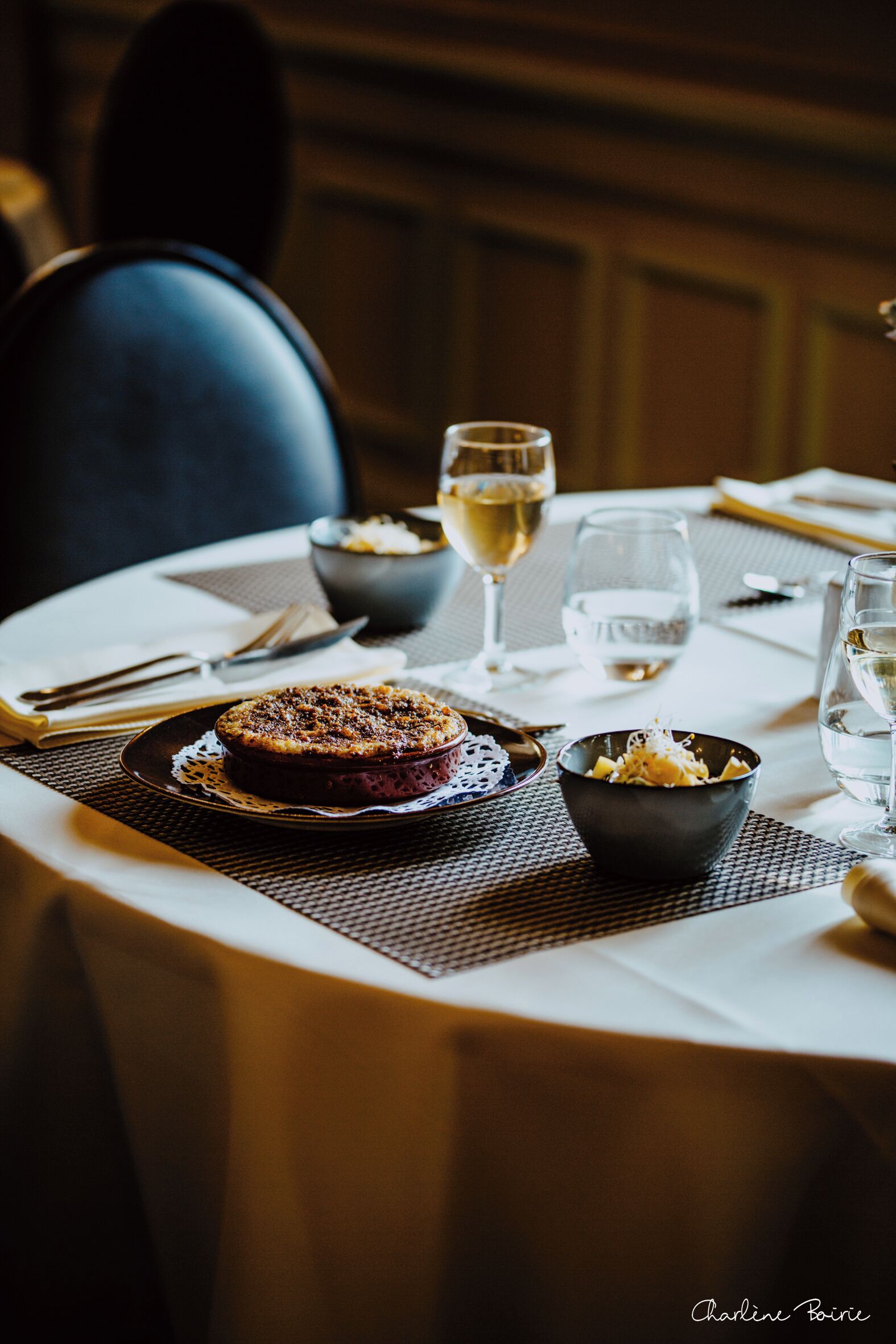 A dining table with a dessert, bowls, and wine glasses.