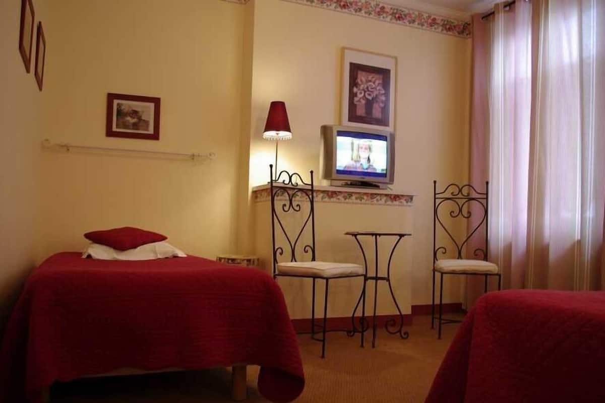 A hotel room with two beds, a TV, a small table, and two chairs.