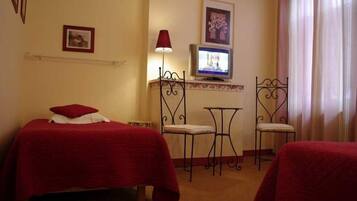 A hotel room with two beds, a TV, a small table, and two chairs.