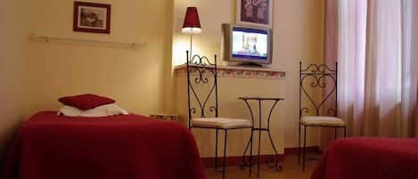 Una habitación de hotel con dos camas, televisión, una mesita y dos sillas.