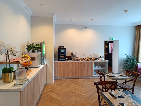 A hotel lobby with a reception desk, a coffee machine, and a buffet area.