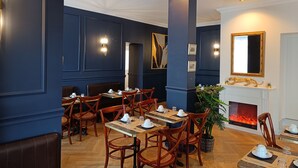 A restaurant with dark blue walls, wooden chairs, and tables set for dining. - The Originals Boutique, Hôtel d'Angleterre, Fécamp (Fecamp)