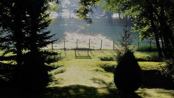 A pathway leading to a bench in a wooded area with a fence and trees.