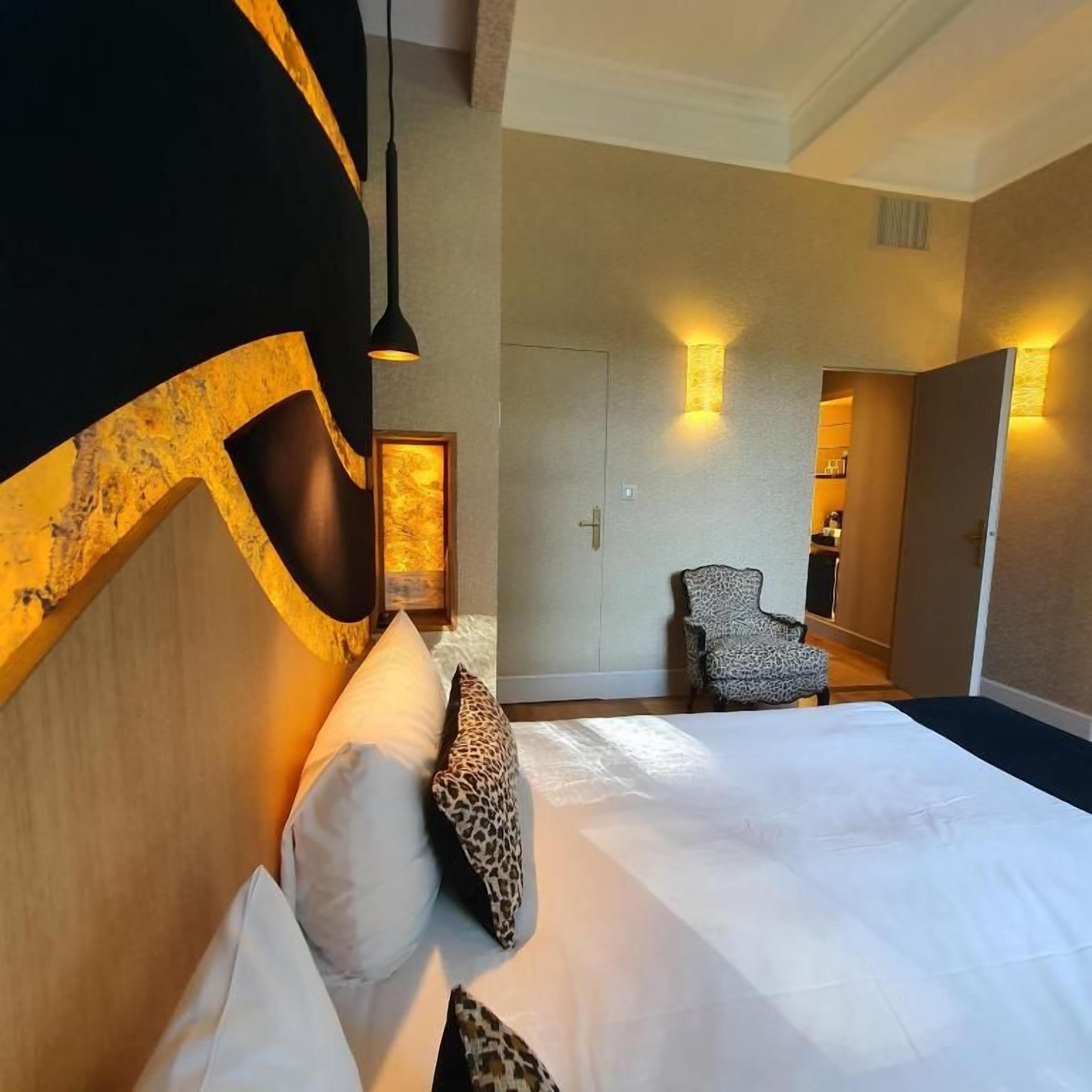 Ein Hotelzimmer mit einem großen Bett, einem Sessel und einer Tür zu einem Badezimmer.