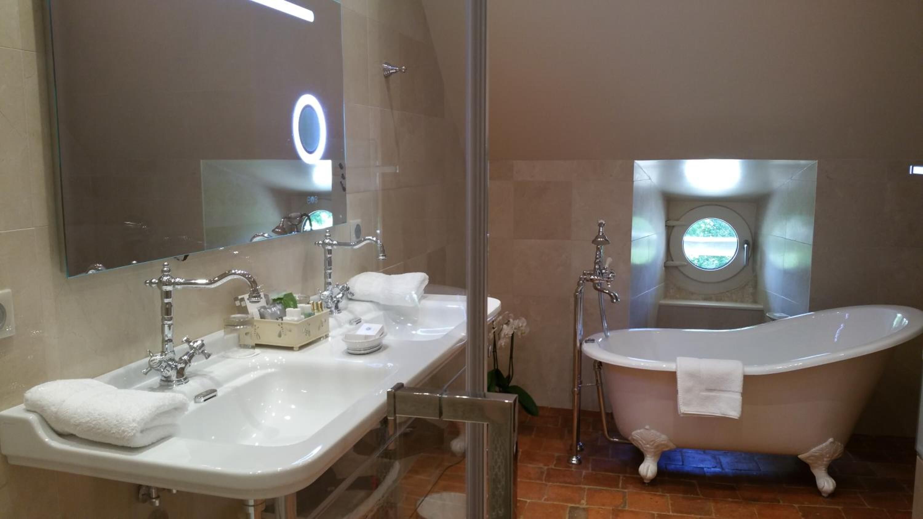 A bathroom with a freestanding bathtub, a double sink vanity, and a large mirror.