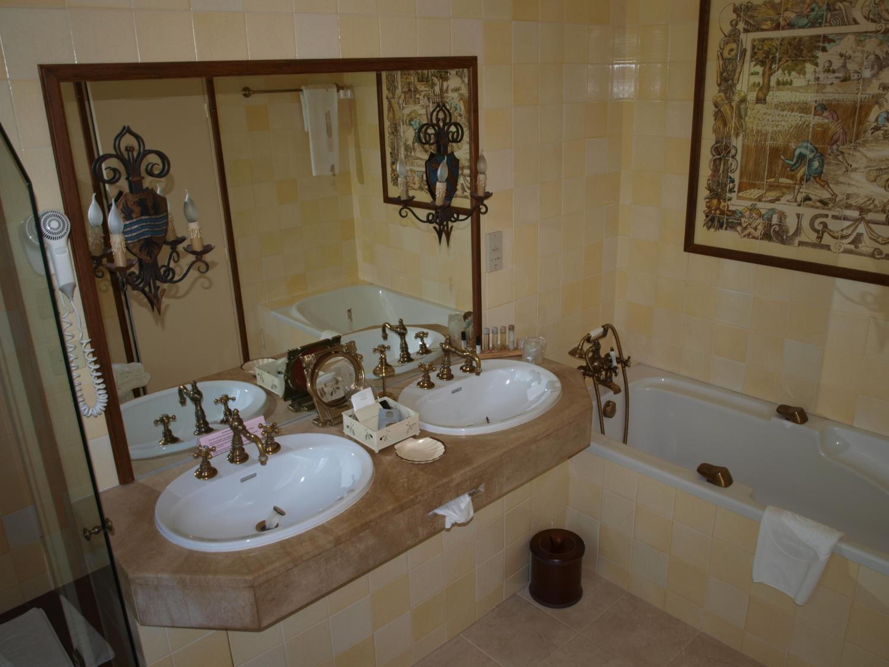 A bathroom with two sinks, a bathtub, a large mirror, and a decorative wall piece.