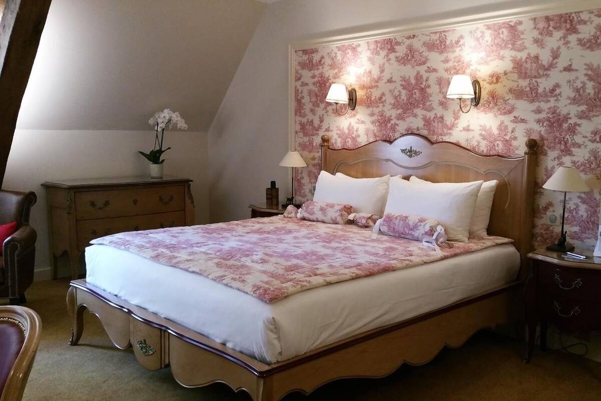 Ein Schlafzimmer mit einem großen Bett, zwei Nachttischen, einer Kommode und einem Sessel.