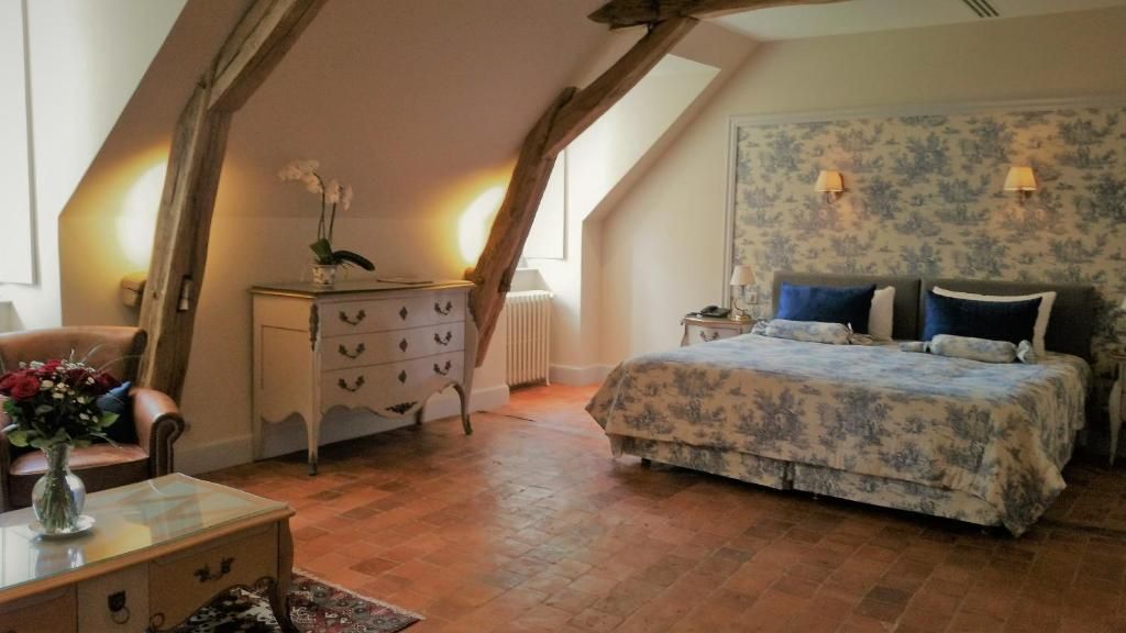 A bedroom with a bed, dresser, and a vase of flowers.