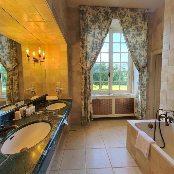 A bathroom with two sinks, a bathtub, and a window with curtains.