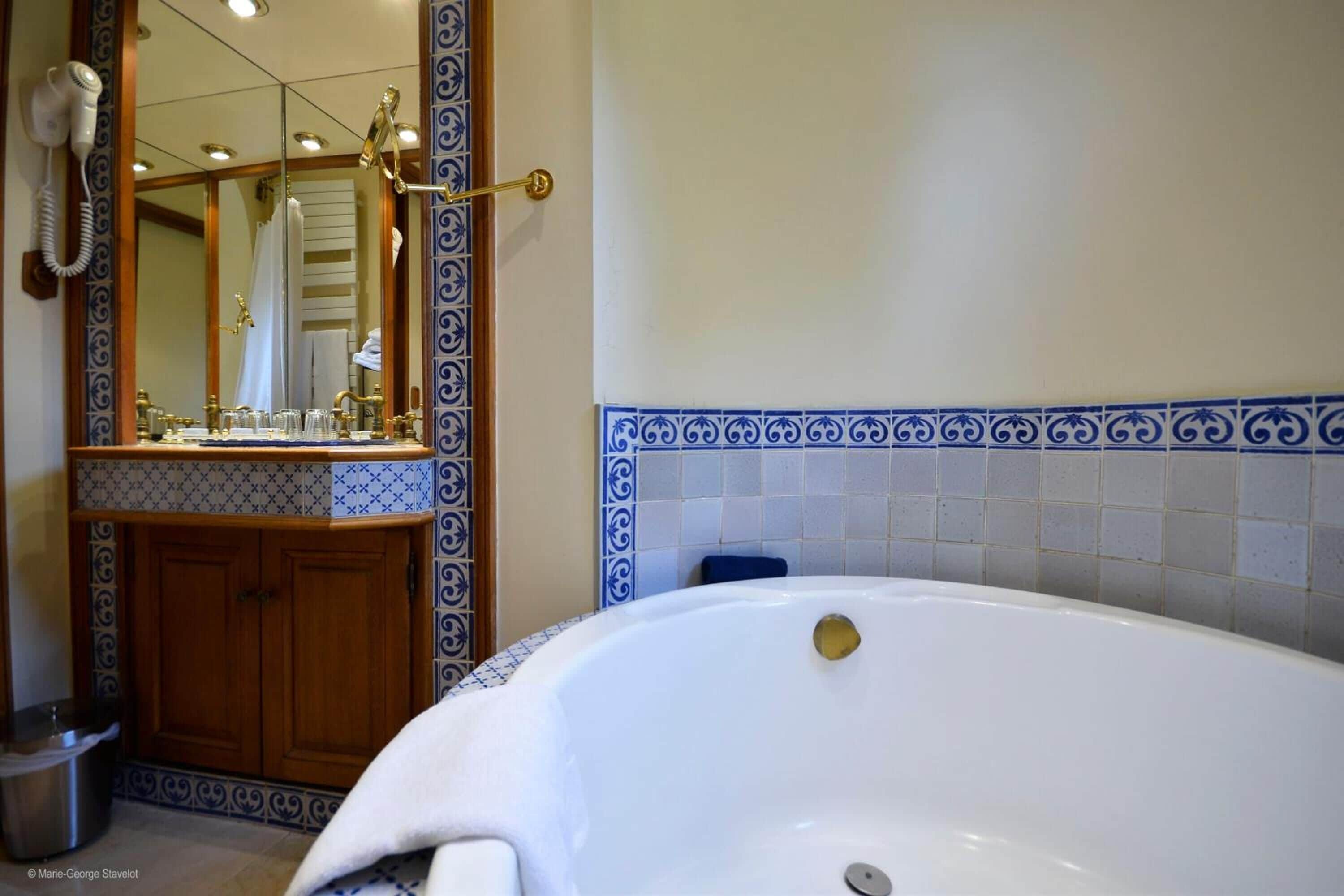 Ein Badezimmer mit einer großen Badewanne, einem Spiegel und einem Waschtisch.