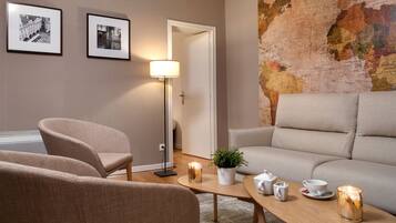 A modern living room with a sofa, armchairs, a coffee table with tea set, and a map on the wall.