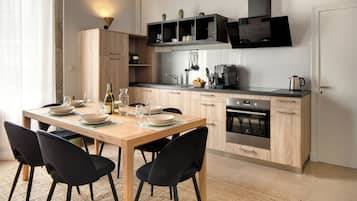 A modern kitchen with a wooden table set for dining, black chairs, and a built-in oven.