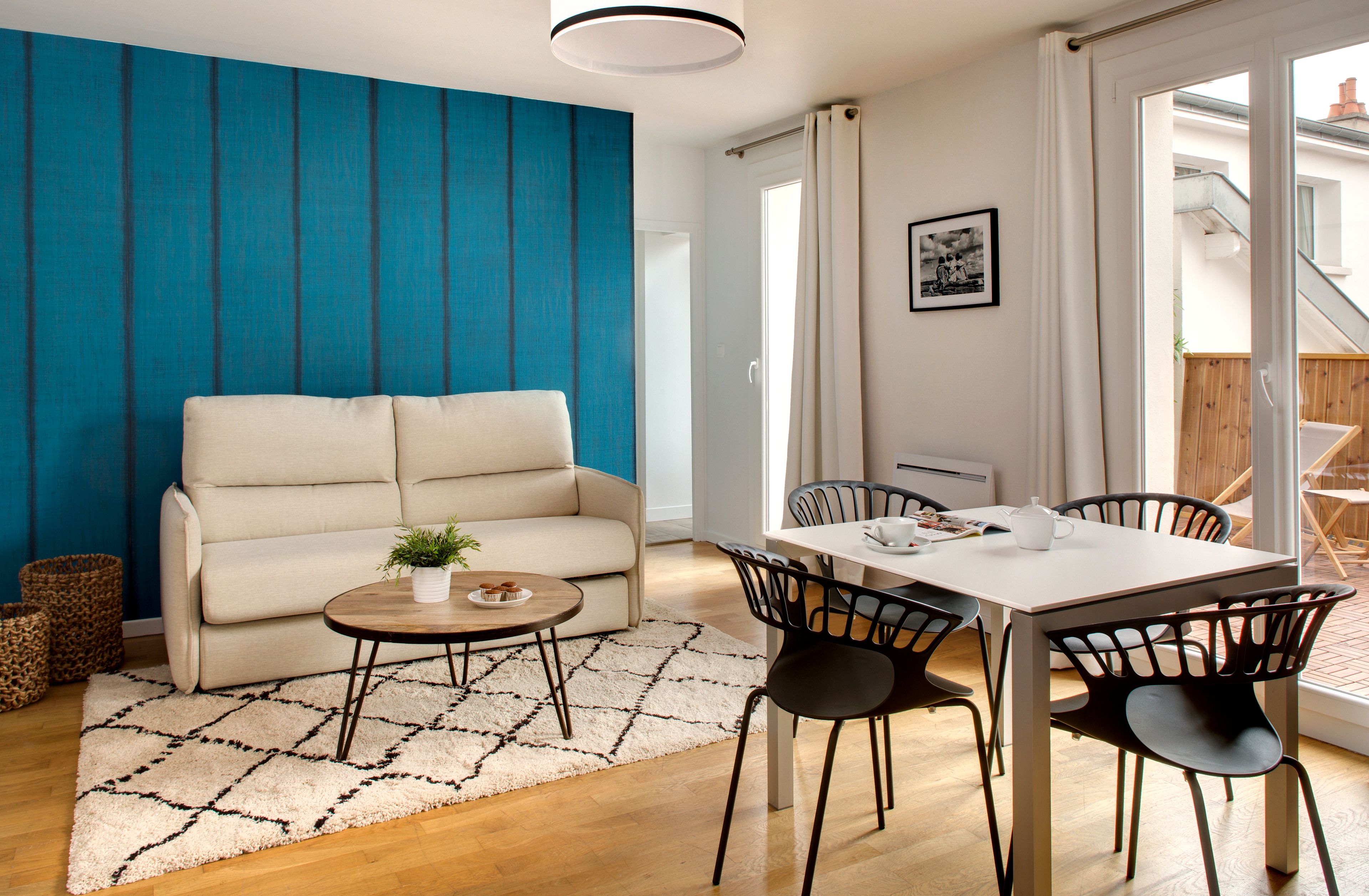 A modern living room with a sofa, a coffee table, and a dining area with chairs.