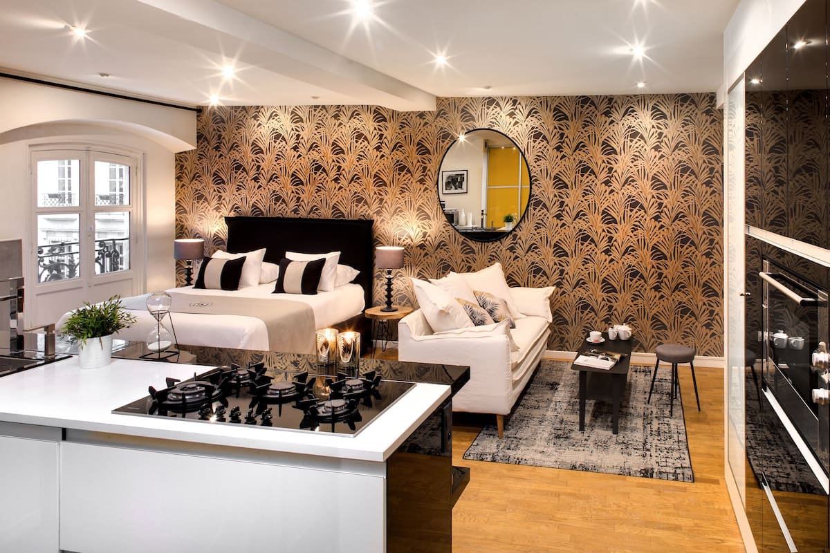 A modern bedroom with a large bed, bedside tables, a desk, and a dining area.