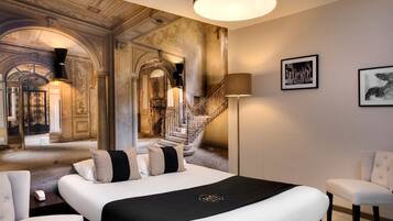 Una lujosa habitación de hotel con una cama grande, una silla, un escritorio y una escalera que lleva a un nivel superior.