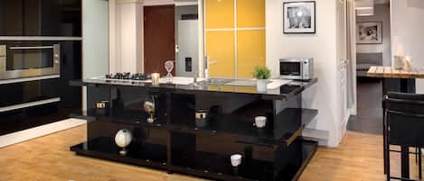 Una cocina moderna con una isla central, electrodomésticos integrados y piso de madera.