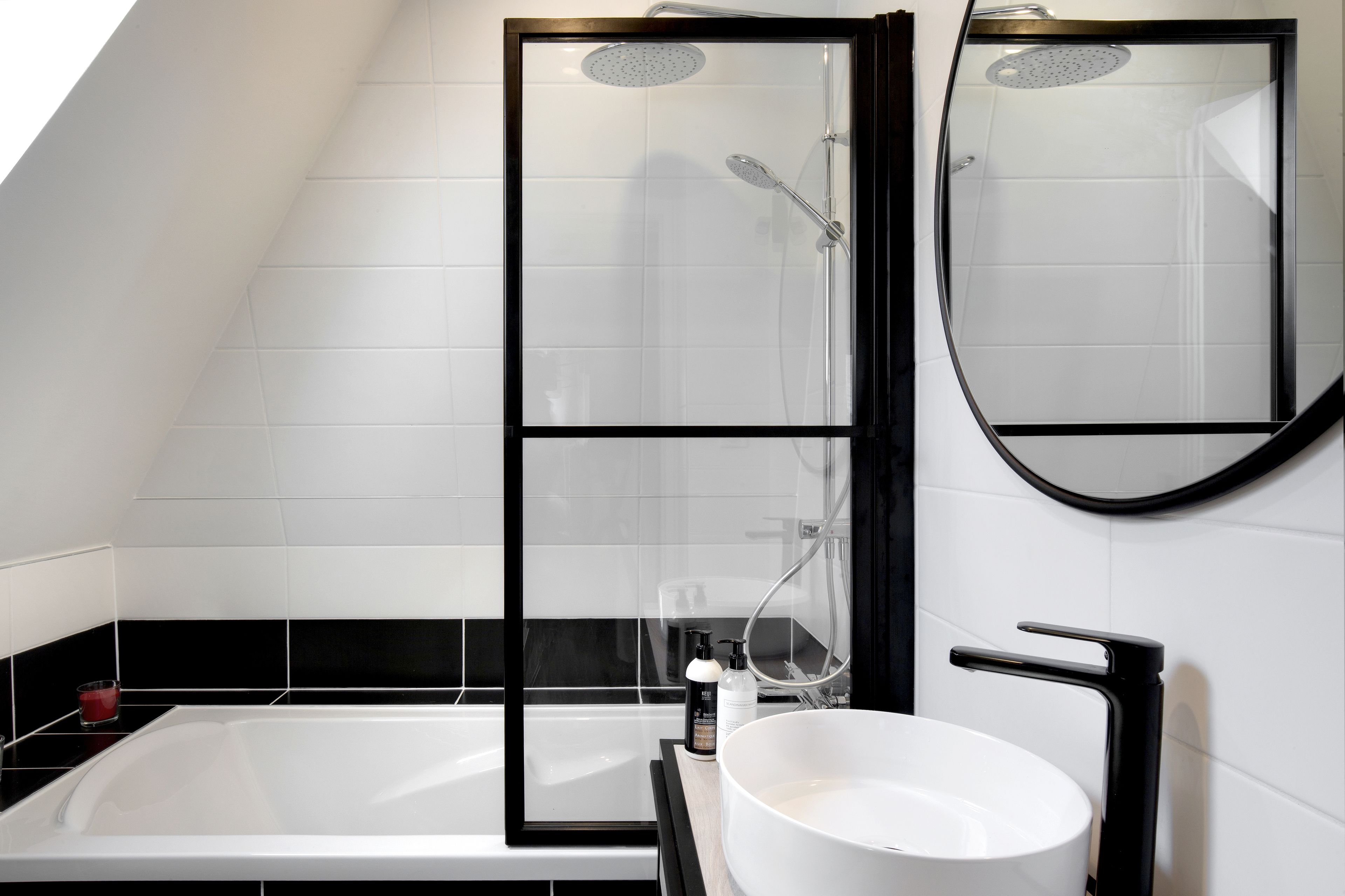 Une salle de bain moderne équipée d’une baignoire, d’un espace de douche, d’un lavabo et d’un miroir.