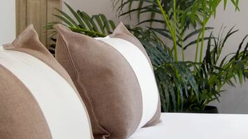 A bedroom with a bed, a hanging light fixture, a mirror, and a potted plant.