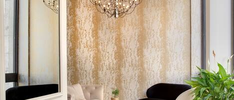 Un salon moderne avec une grande fenêtre, un lustre, un canapé, un fauteuil et une table basse.