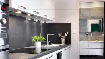 Una cocina moderna con encimera negra, electrodomésticos de acero inoxidable y una planta en maceta.