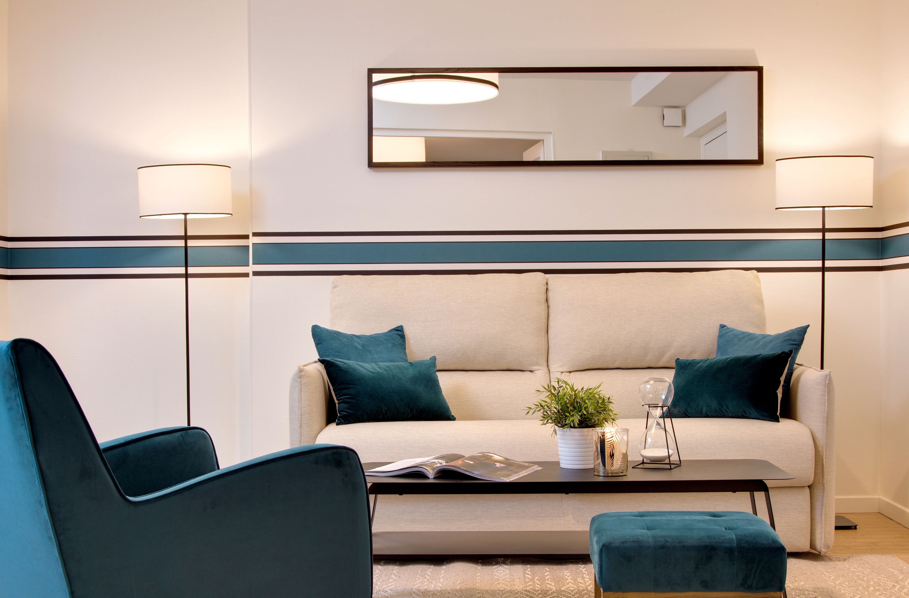 Een moderne woonkamer met een bank, twee fauteuils, een salontafel en een vloerlamp.