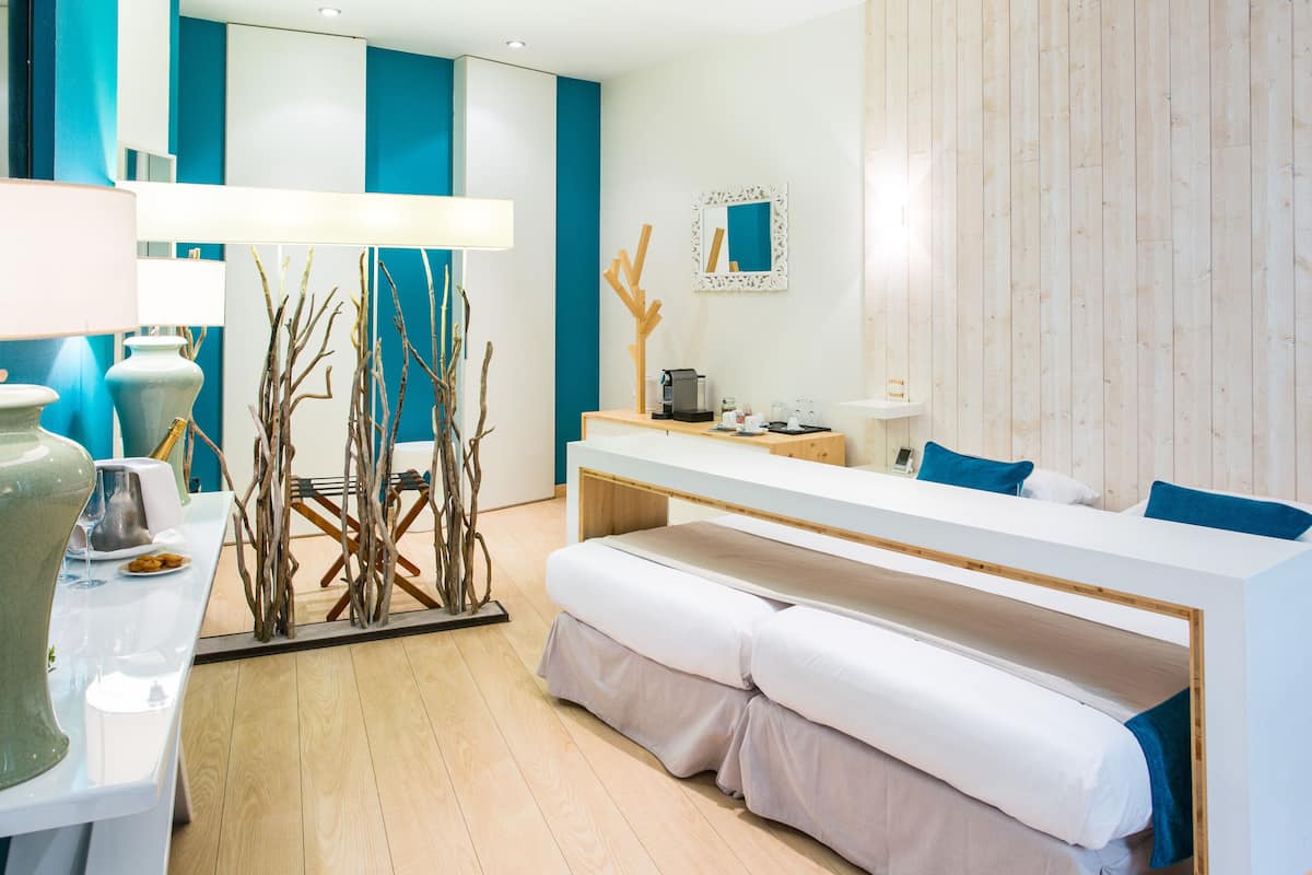 A modern hotel room with a bed, bedside table, lamp, and decorative branches.