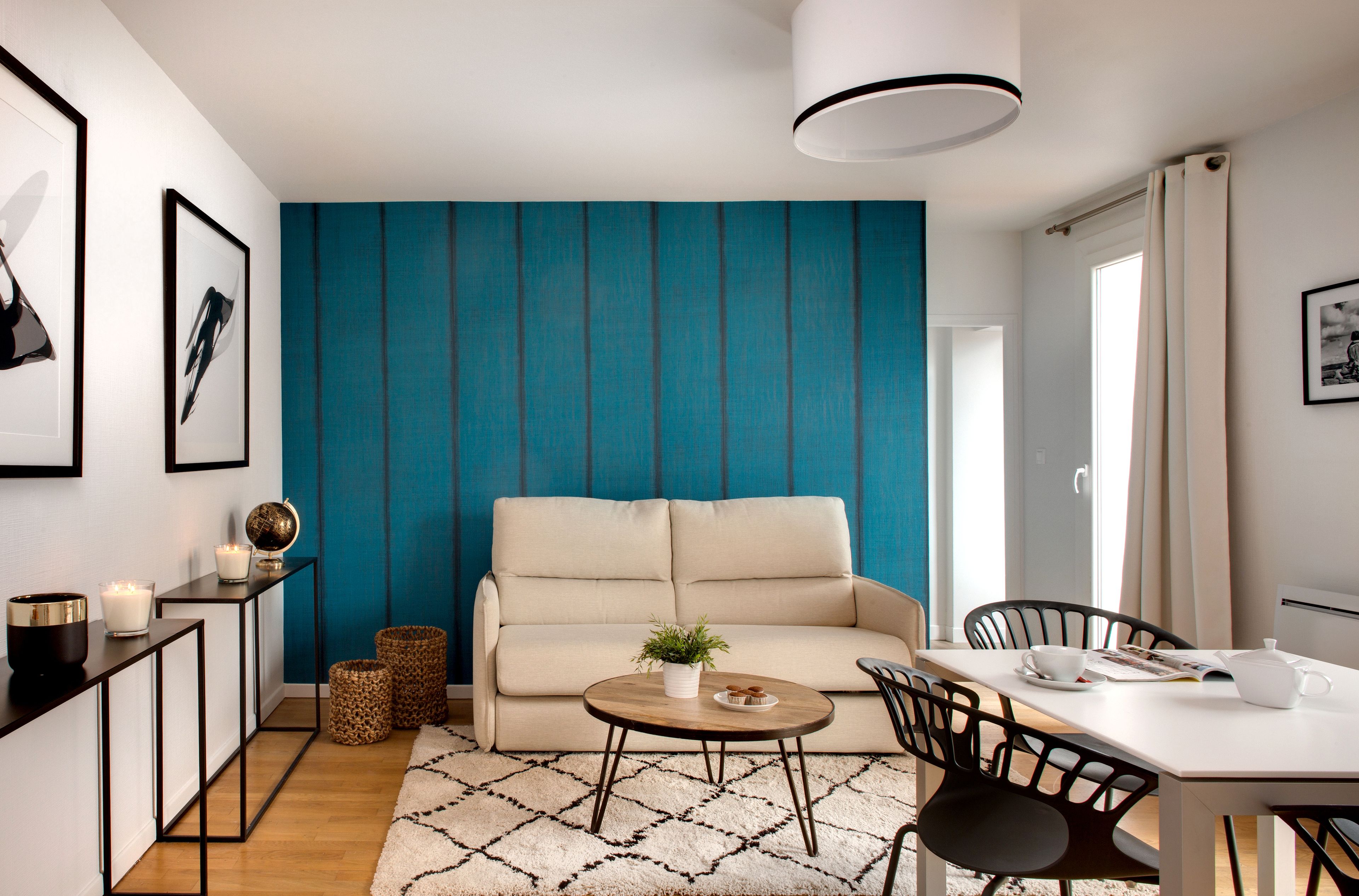 A modern living room with a beige sofa, a round coffee table, and a dining area with a white table and chairs.