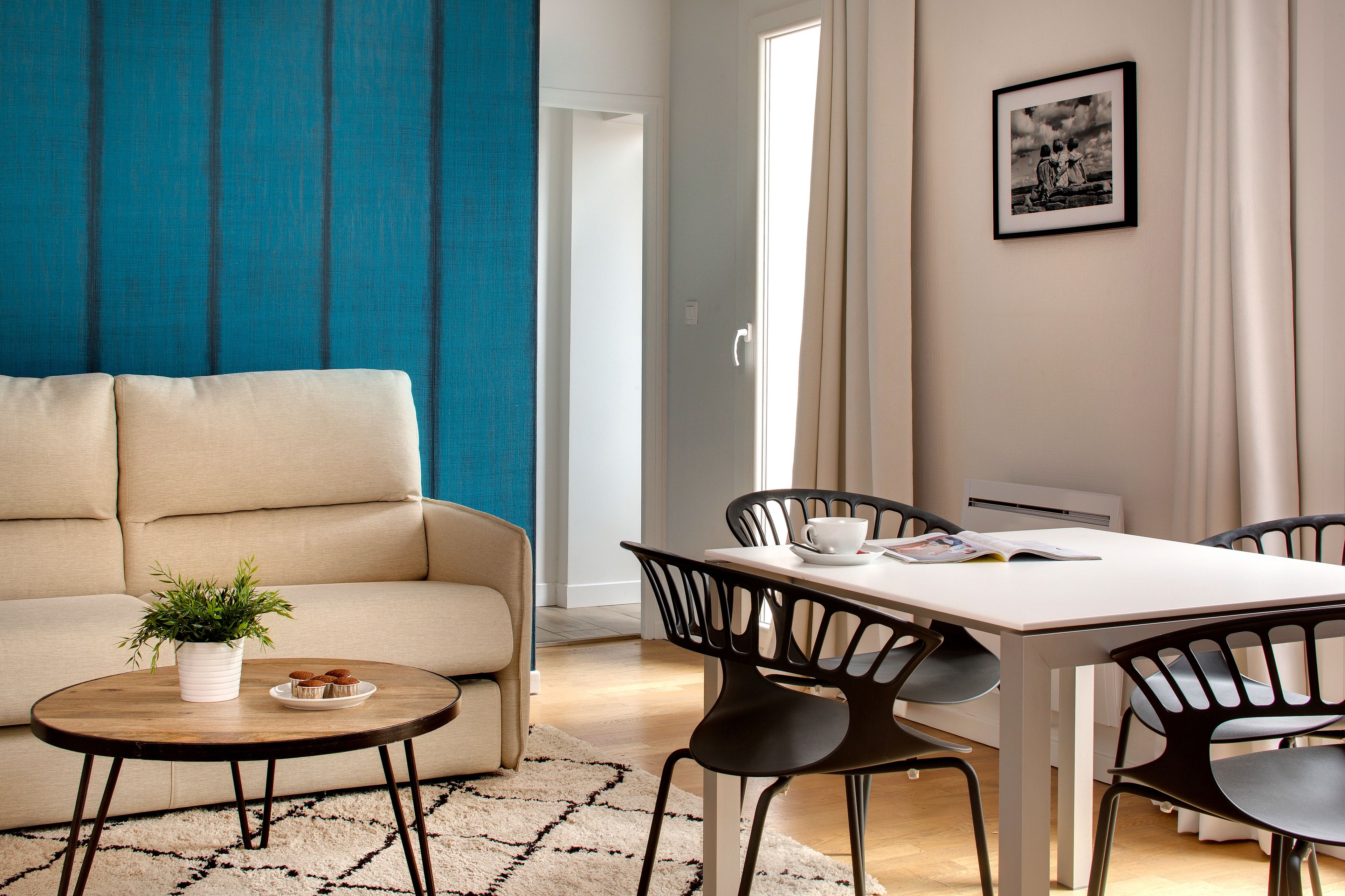 Una sala de estar moderna con un sofá, una mesa de centro con una planta y un comedor con una mesa y sillas.