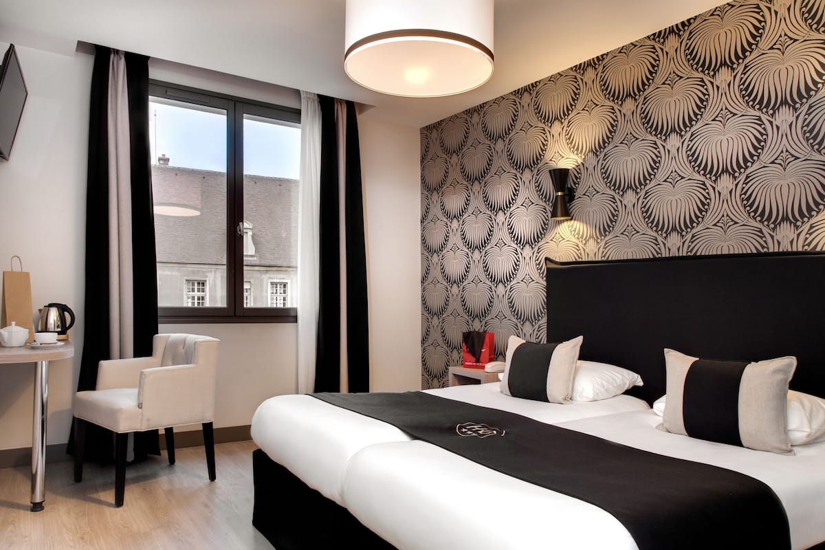 A modern hotel room with a large bed, a desk, and a chair.
