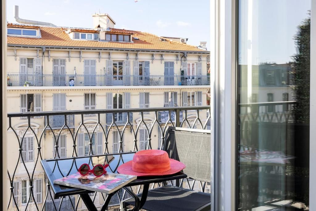 Ein Balkon mit Tisch, Stuhl und einem roten Hut.