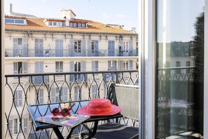 A balcony with a table, a chair, and a red hat. - Hotel 64 Nice (Nice)