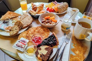 A breakfast table with various foods, including bread, pastries, and a bowl of mixed nuts and dried fruits. - Hôtel de France, un hôtel AMMI (Nice)