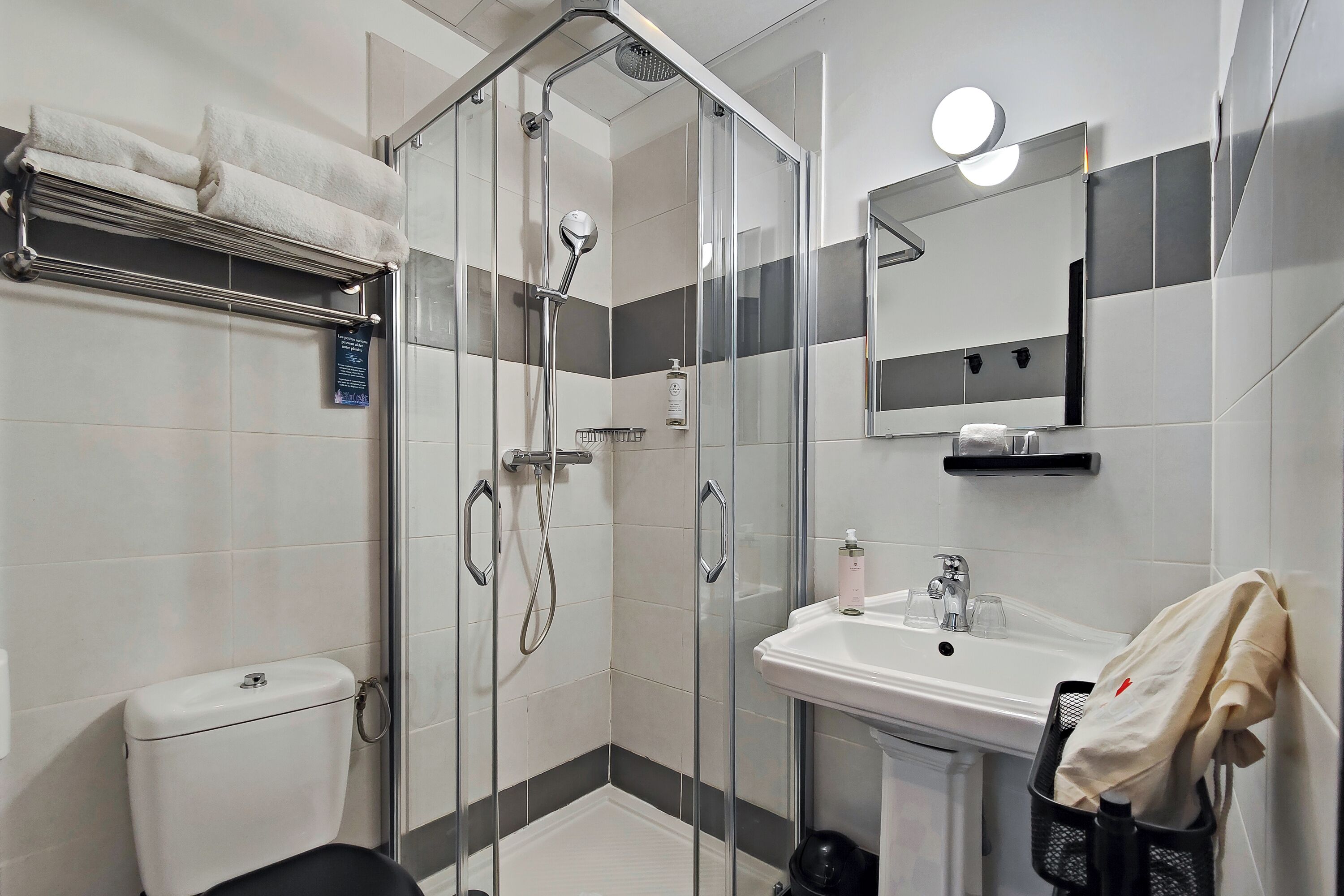 A modern bathroom with a glass-enclosed shower, a white sink, and a mirror above it.
