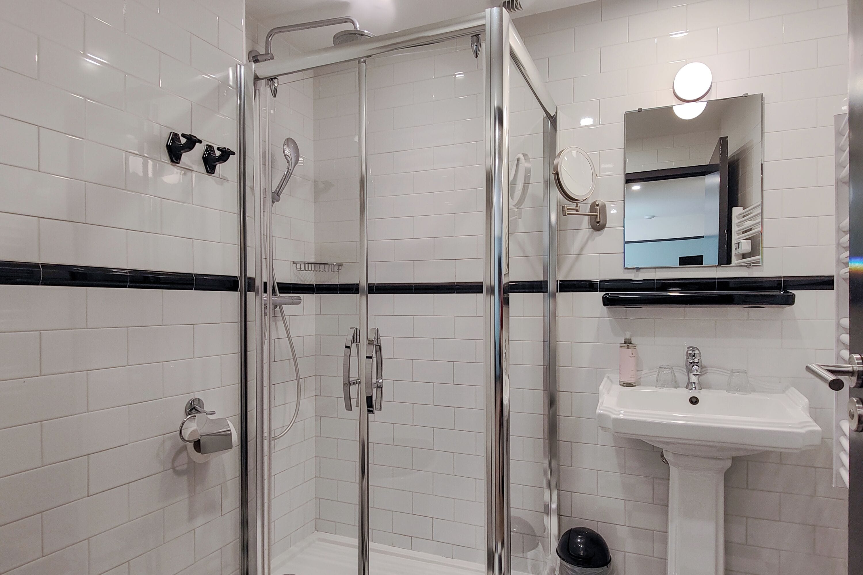 Un baño moderno con ducha envuelta en vidrio, un lavamanos blanco y un espejo sobre él.