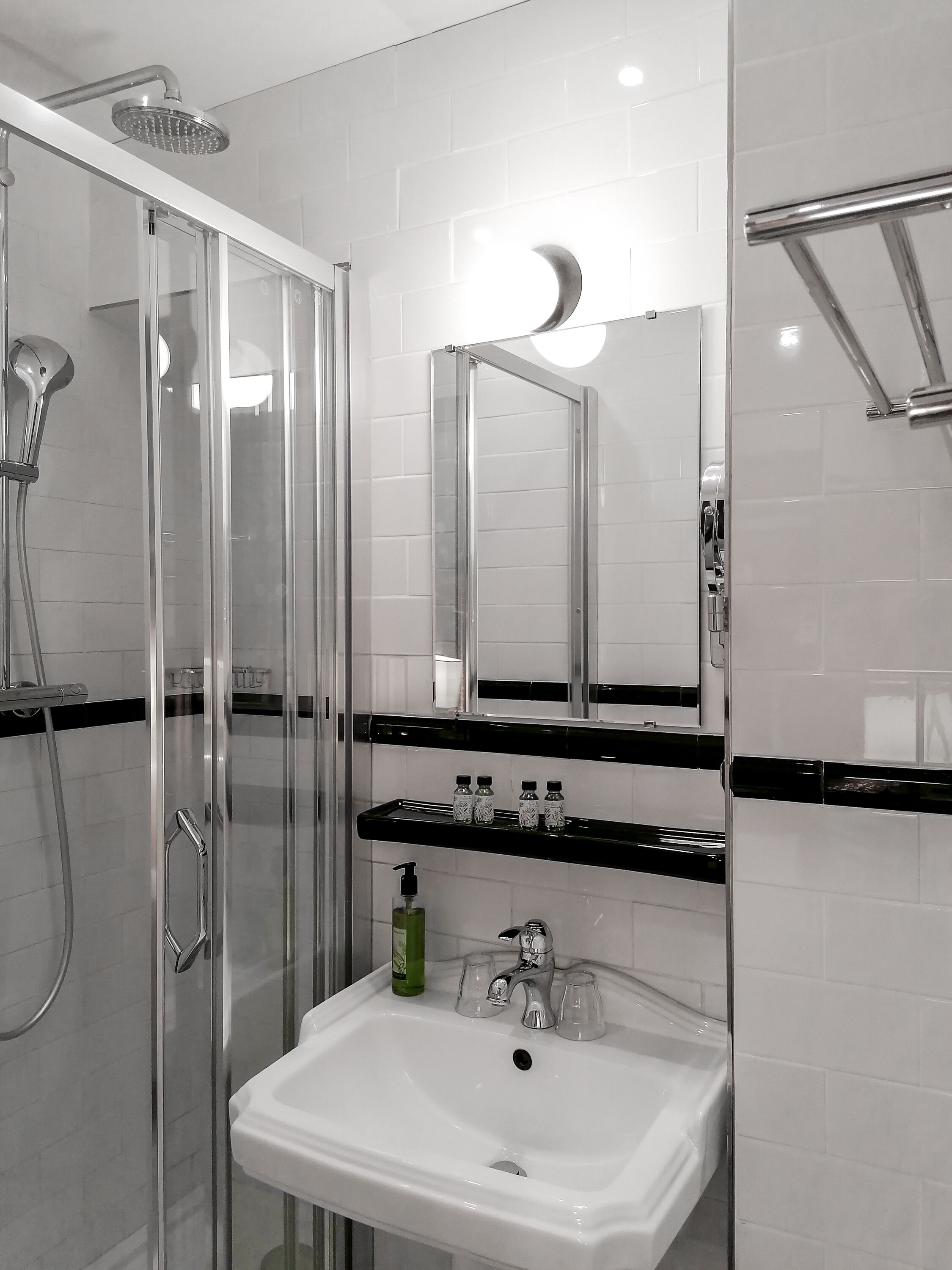 Un baño moderno con ducha de vidrio, un lavabo blanco y un espejo encima.