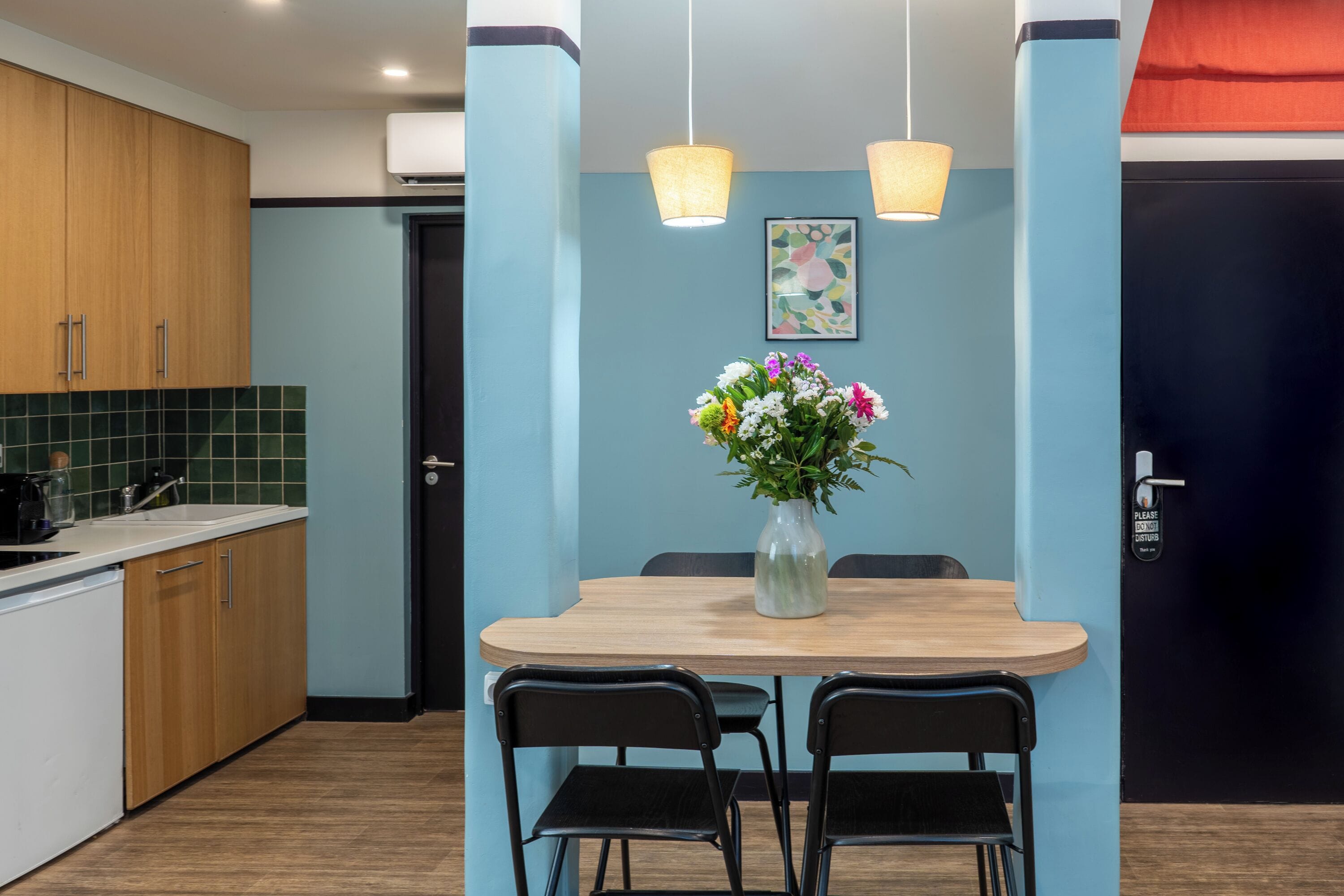 Een moderne keuken met houten kasten, een zwart aanrecht en een eethoek met een houten tafel en zwarte stoelen.