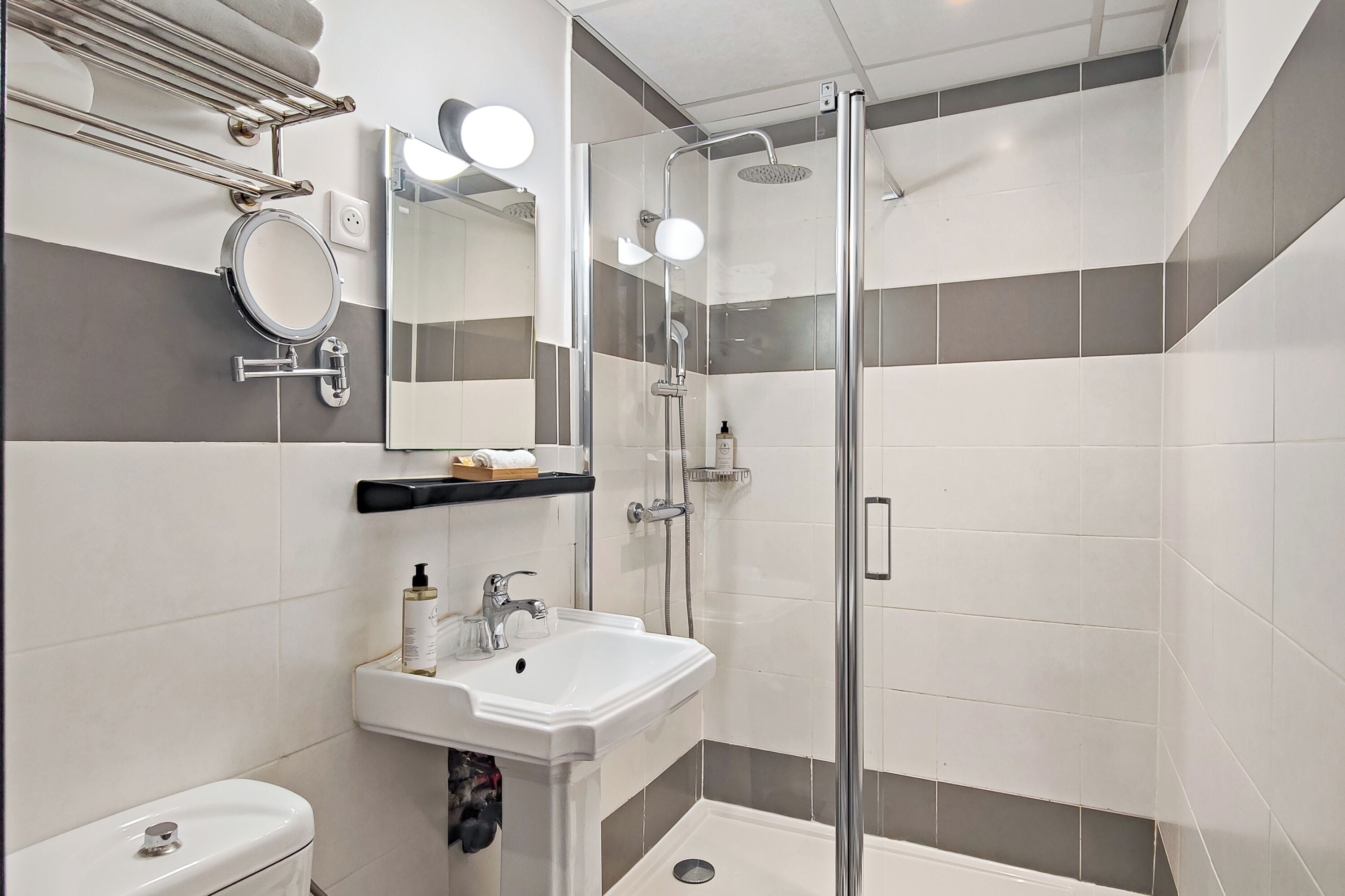 A modern bathroom with a glass-enclosed shower, a white sink, and a mirror.
