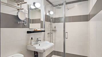 A modern bathroom with a glass-enclosed shower, a white sink, and a mirror.