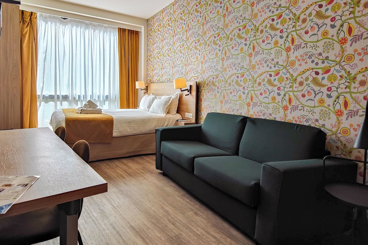 Ein Hotelzimmer mit einem Bett, einer Couch, einem Tisch und einer Wand mit Muster.