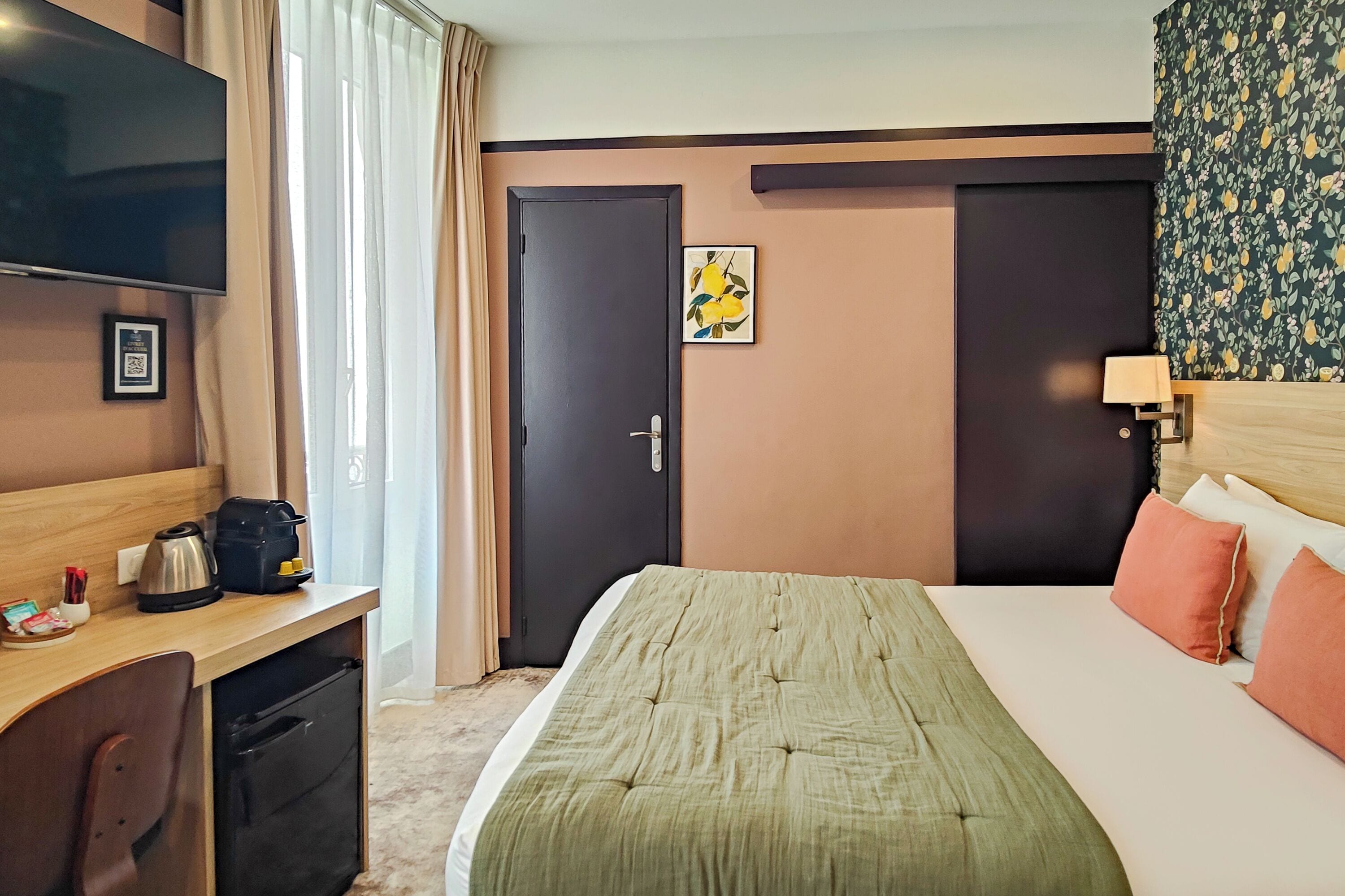 Une chambre d’hôtel avec un lit, un bureau, une télévision et une porte.