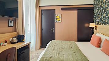 Une chambre d’hôtel avec un lit, un bureau, une télévision et une porte.