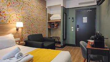 Een hotelkamer met een bed, een bureau met stoel, een bank, een kledingkast en een deur met slot.