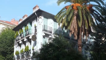 A historic building with a balcony and a palm tree in front.