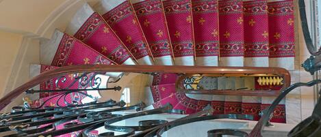 A spiral staircase with ornate metal railings and pink patterned steps.