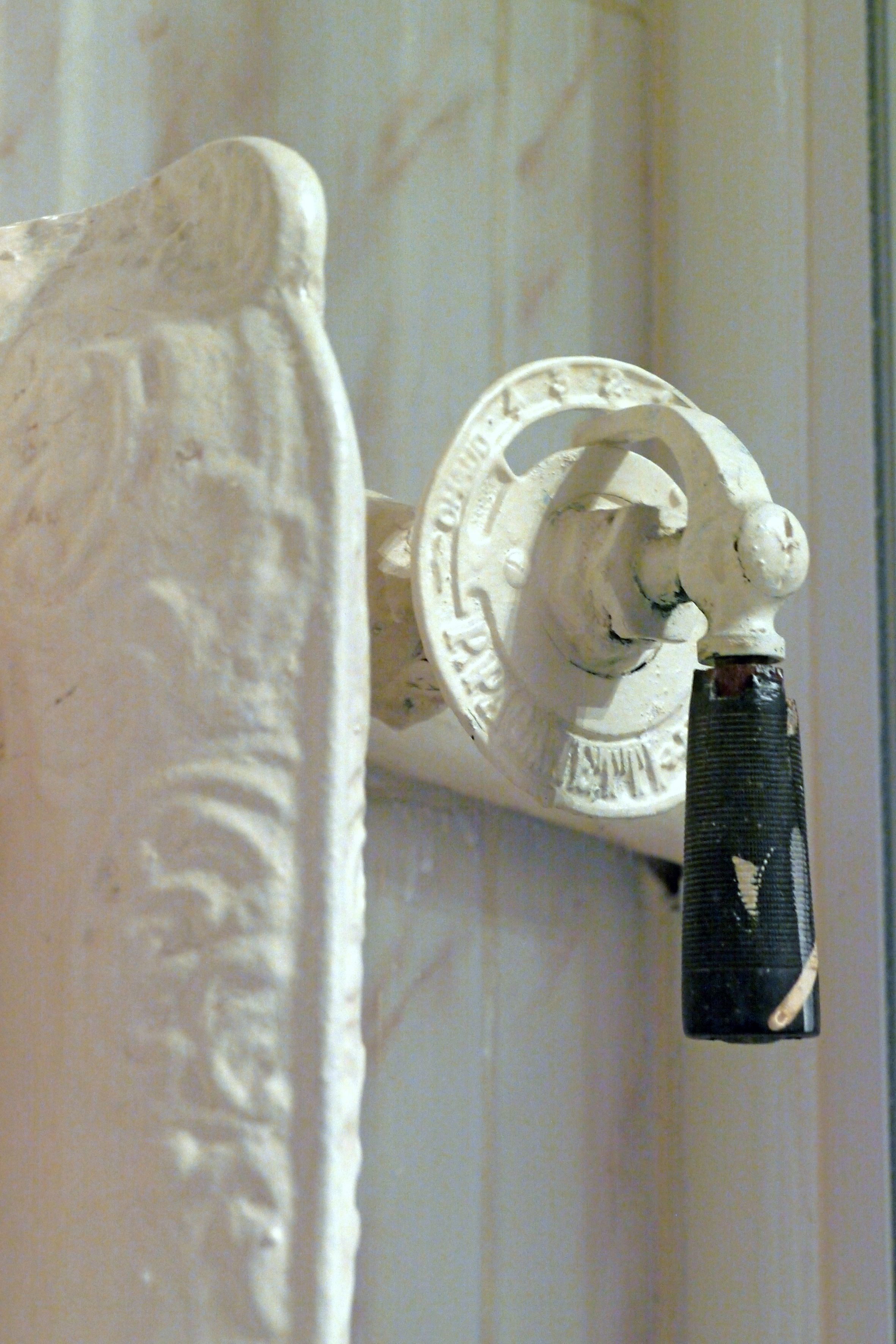 Una ornamentada fijación de pared blanca, con un diseño circular y un pomo negro.