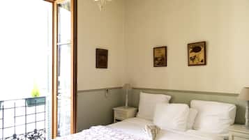 Ein Hotelzimmer mit Bett, Nachttischen, einer Chandelierleuchtre und Kunstwerken an den Wänden.