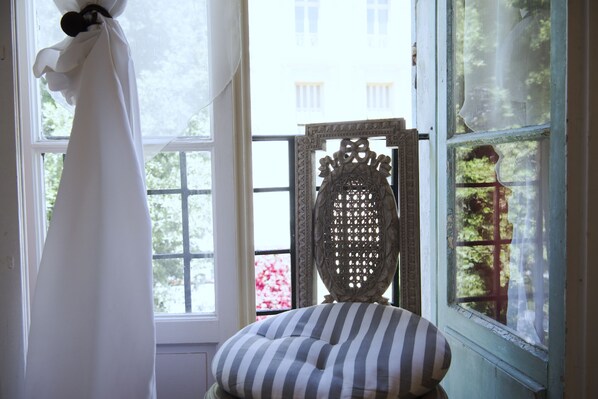 A room with a window, a chair, and a curtain.