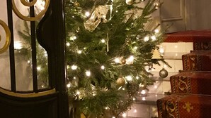 A Christmas tree with lights and ornaments, placed in front of a staircase with wrapped gifts. - Villa Rivoli (Nice)