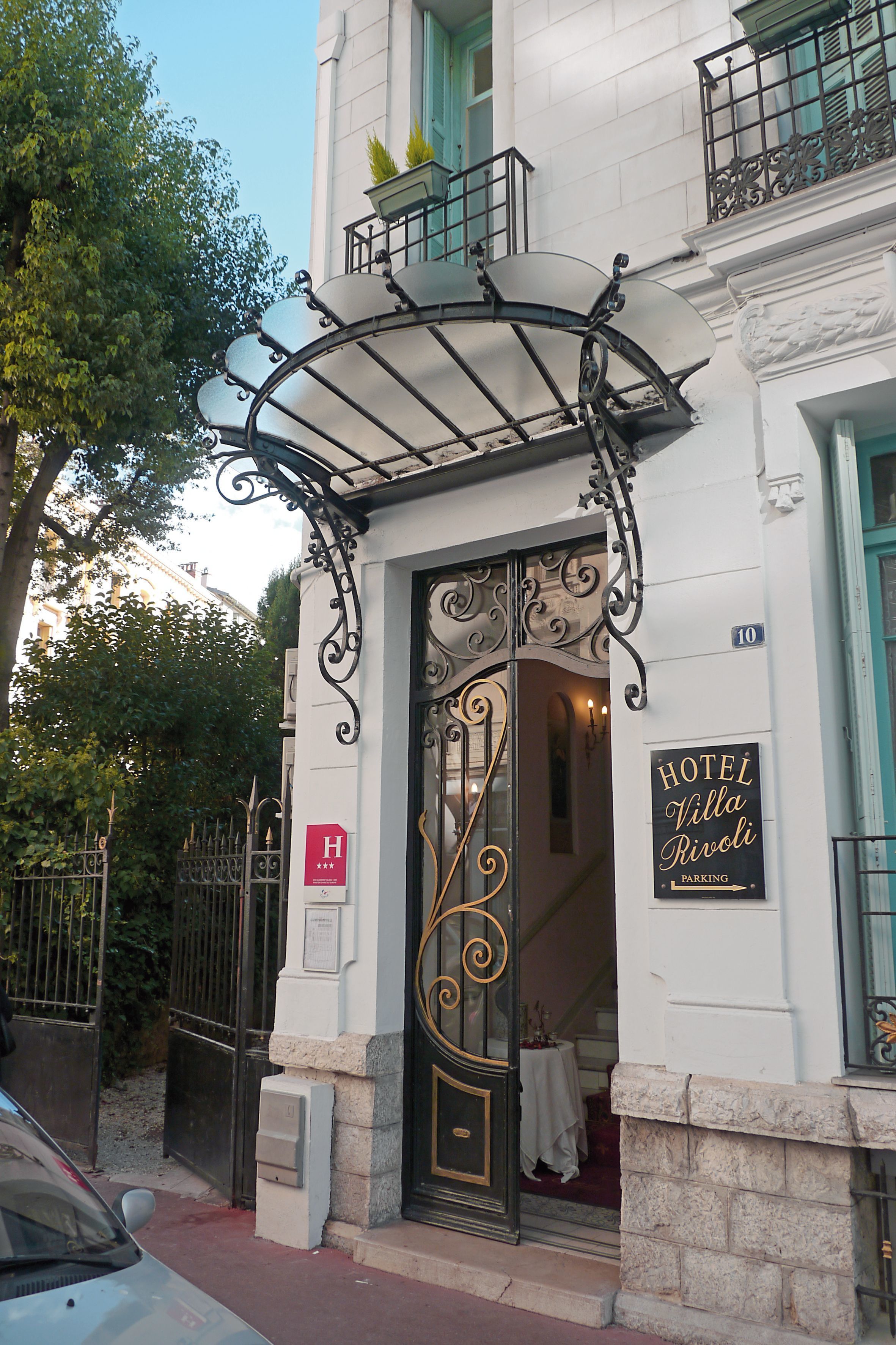 A hotel entrance with ornate ironwork, a sign indicating it is a hotel, and a visible address number.